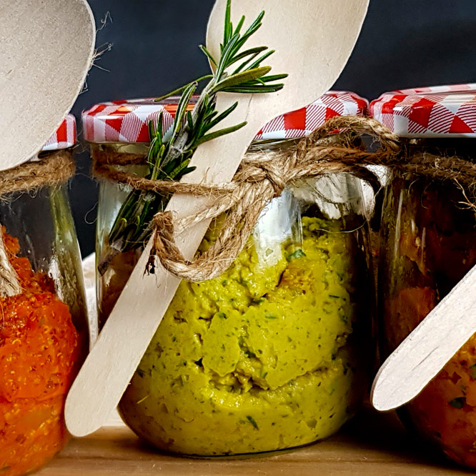 Zucchini-Reis Aufstrich Leuchtend grüner, leckerer Zucchiniaufstrich mit Reiswaffeln. Angerichtet in einem schönen Einmachglas mit Kräutern und Holzlöffel dekoriert