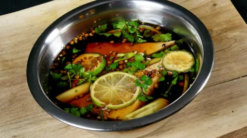 Eine Marinade mit Zitronenscheiben und Kräutern